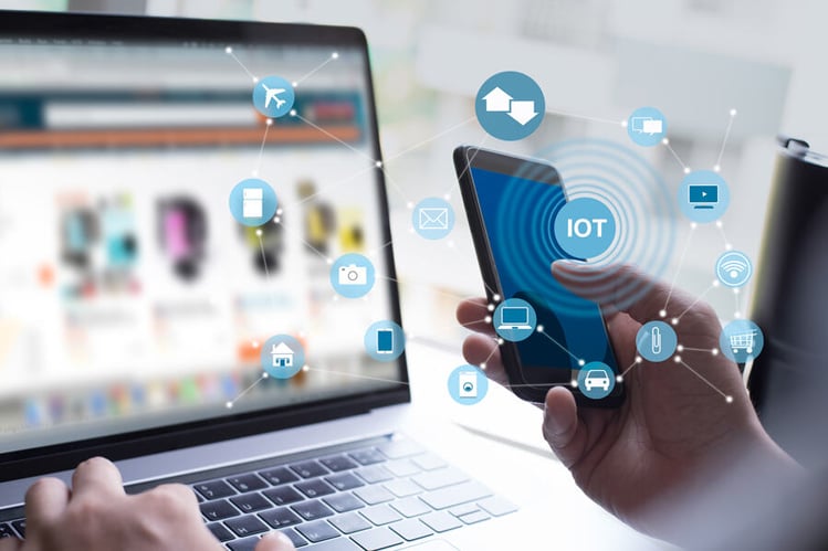 Zwei Hände mit Laptop und Smartphone, darüber liegt eine IoT Infografik