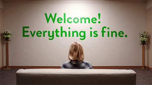 Woman sitting on couch and reading a quote on a white wall saying "Everything is Fine."
