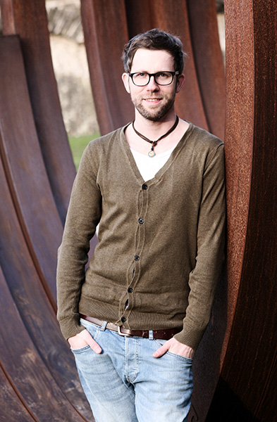 Mann mit Brille und Bart in Jeans und Strickjacke